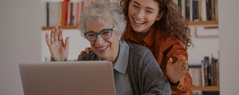 uma idosa mexendo em um notebook juntamente com uma jovem